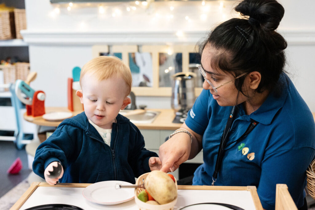 A nursery member of staff with a child