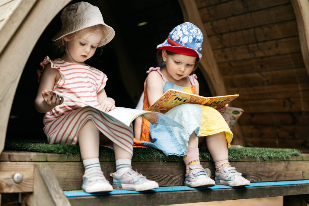 Two children outside reading.